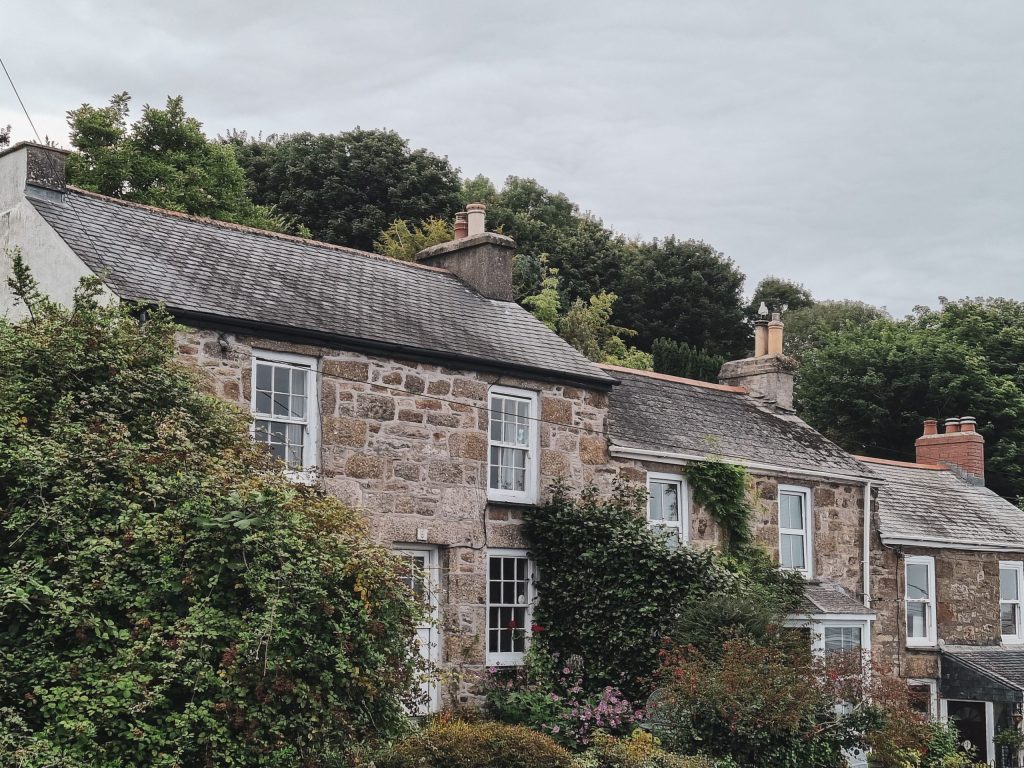 Ivy-covered stone house in Newlyn, England, showcasing traditional architecture and lush garden plants.
